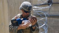 A US Marine comforts an infant while waiting for his mother during an evacuation at Kabul airport 