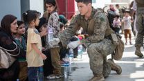 An American Marine gives fresh water to a child
