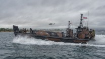 A Wildcat helicopter flies alongside in support