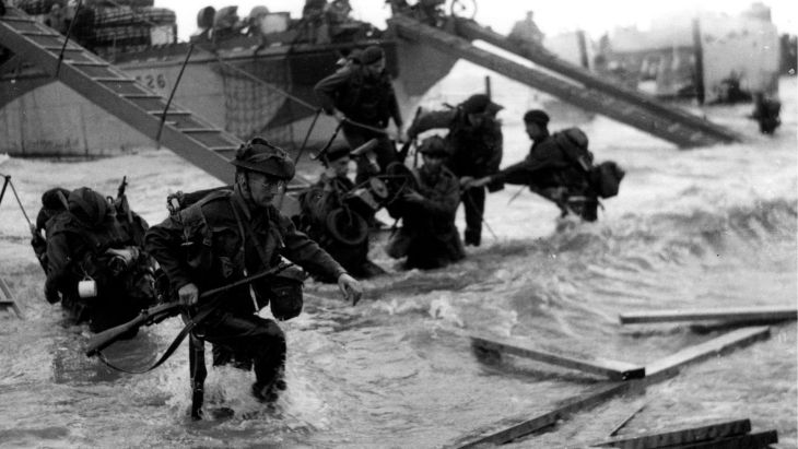 Personnel from No. 48 (Royal Marine) Commando wade through the surf and debris as they come ashore during D-Day (Picture: Royal Navy)