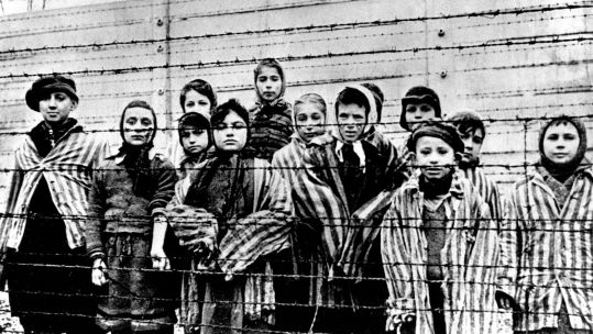 040226 child prisoners wearing striped uniforms stare out from behind a barbed wire fence in Auschwitz Southern Poland Holocaust NO REUSE Image ID T9K64D CREDIT Shawshots Alamy Stock Photo