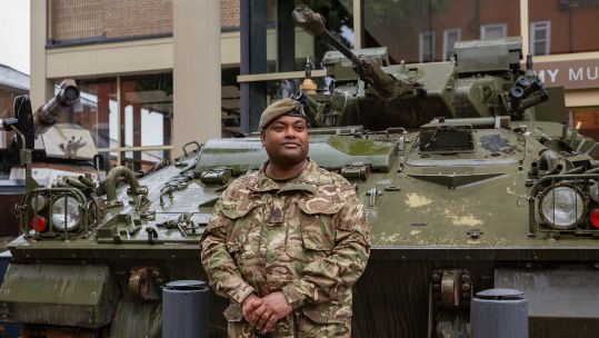 WO1 Beharry stands beside the Warrior infantry fighting vehicle in which he managed to save the lives of his fellow soldiers on two separate occasions (Picture: National Army Museum)