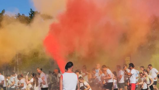 Runners starting off the colour run at Depsey Barracks, running through a haze of orange, pink and yellow paint