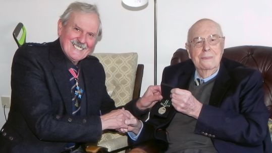 Mr John Cruickshank VC, 103, receives his long overdue Air Efficiency Award from Group Captain (retd) Bob Kemp of the Royal Auxiliary Air Force Foundation. 