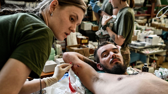A Ukrainian medic extracts a piece of metal from the body of a serviceman at a stabilisation point in the Zaporizhzhia Region (Picture: Ukrinform)