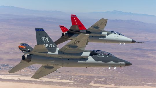 A T-7A Red Hawk (with red tail) and BTX-1 prototype fly together over Edwards Air Force Base - but the T-7 could end up flying over RAF Valley too
