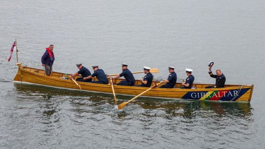Commander Chris Bate is rowed ashore in the traditional ceremony 