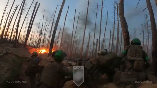 Azov Brigade soldiers stand back as one of their grenades explodes before the move further forward into a Russian trench system