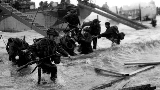 Personnel from No. 48 (Royal Marine) Commando wade through the surf and debris as they come ashore during D-Day (Picture: Royal Navy)