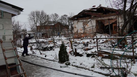 A man cleans debris around a damaged building after Ukrainian forces' attack in Lgov of Russia's Kursk region