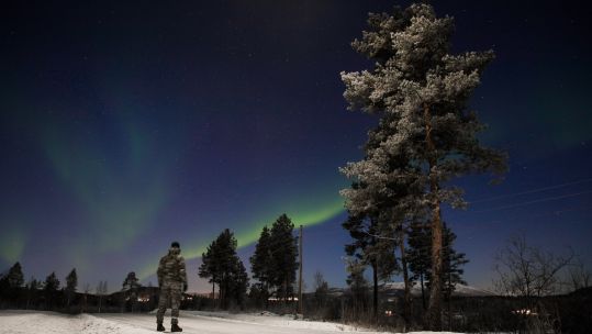 A Royal Marine from 45 Commando stands under The Northern Lights (aurora borealis) during the units Winter Deployment in Bardufoss, Norway.