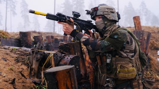 A French infanteer works her way through a trench armed with her HK416 assault rifle