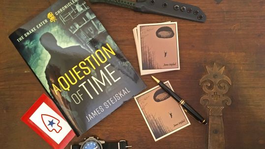 Desk with a book entitled 'A Question of Time', some cards, a watch and other items on