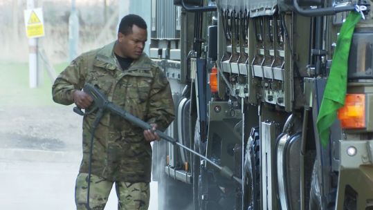 A RLC soldier cleans a vehicle. 
