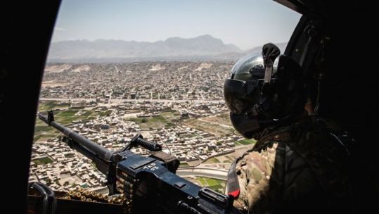  Royal Air Force door gunner watches over the city of Kabul whilst a Puma flies over, Afghanistan Op Toral draws to a close 