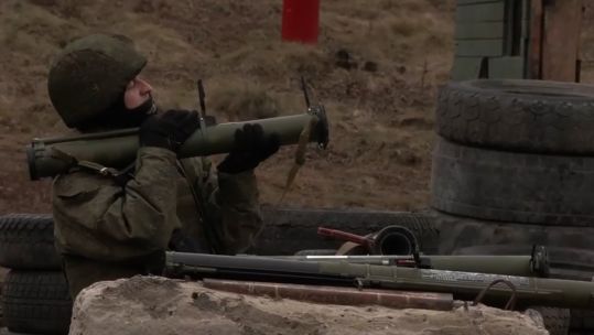 A Russian soldier looks up to fire his weapon 