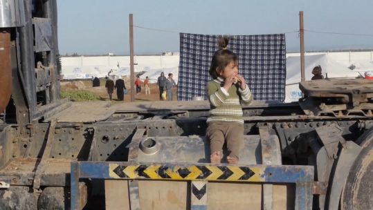 A Syrian girl sits on old pieces of metal (Picture: UNICEF).