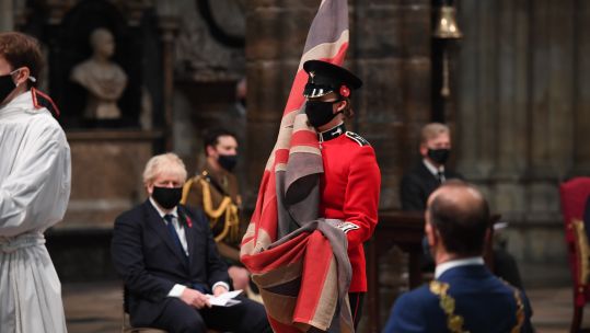 A flag bearer at Westminster Abbey in London with Boris Johnson in background, during a service to mark Armistice Day and the centenary of the burial of the Unknown Warrior