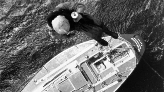 A helicopter crewman hangs from a winch to check the battered yacht Grimalkin for possible survivors in the wake of the Fastnet race disaster HD 200819 CREDIT PA .