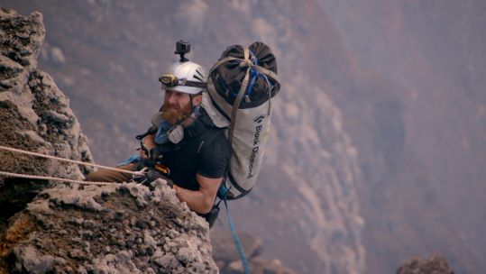 Aldo Kane climbing a rock face.