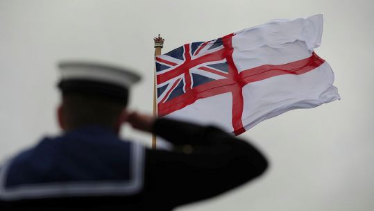 Royal Navy sailor salutes the White Ensign