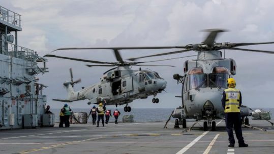 Anonymous military personnel and Merlin helicopters on the flight deck of RFA Argus whilst flying crucial disaster relief sorties to Honduras (Picture: MID