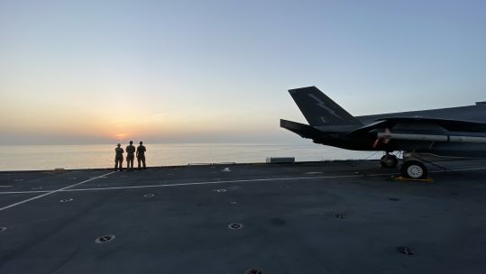 Anonymous personnel at sunrise on the flight deck of HMS Queen Elizabeth.
