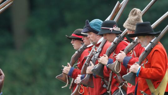 English Civil War re-enactors in red coats and with muskets