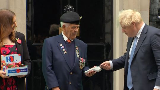 Boris Johnson buys a poppy (Picture: Reuters).
