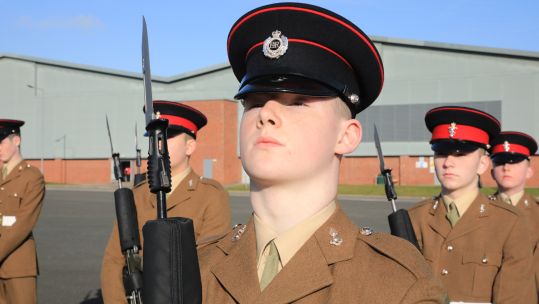 A soldier stands to attention with his rifle