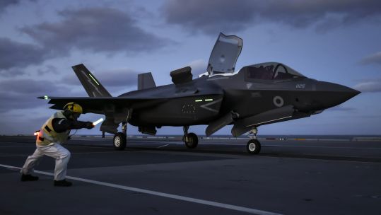 HMS Queen Elizabeth flight deck officer gives the signal to launch. F35-B jets of 617 Squadron conduct night flying sorties, working in pairs