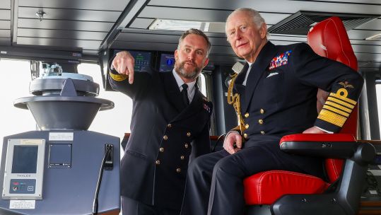 Commanding Office Captain Will Blackett shows King Charles the controls on the HMS Prince of Wales