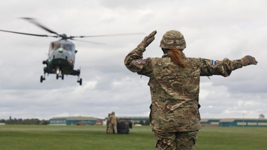 Hair Ponytail Female Air Trooper, part of HQ Sqn, 6 AAC marshaling a Wildcat Helicopter onto a netted load Credit Defence Imagery ID 45164379