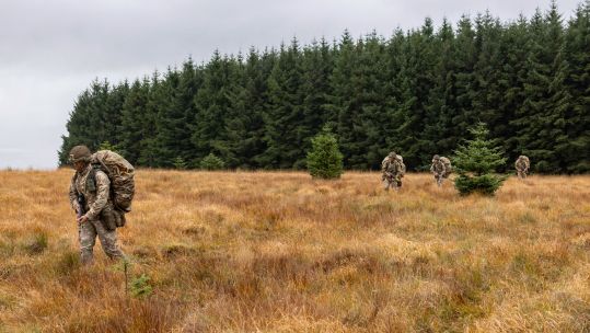 Fully ladden soldiers moving across open ground during Exercise Cambian Patrol