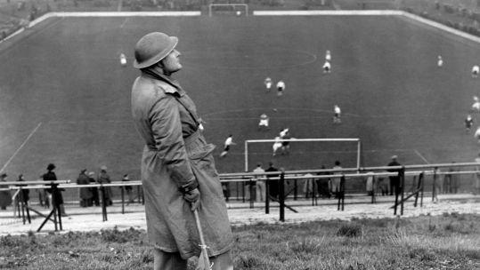 A lookout watches for attack during a football match in WW2. Alamy