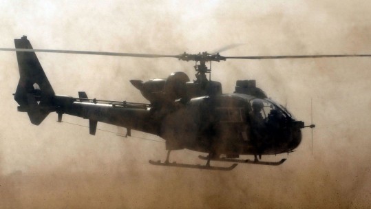 A Royal Marines Gazelle helicopter kicks up a storm at a desert air base