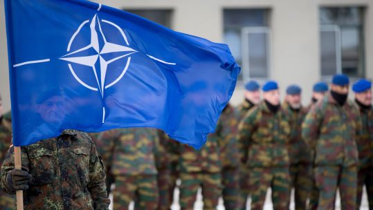 German soldiers hoists the NATO flag to greet the German minister of Defence 