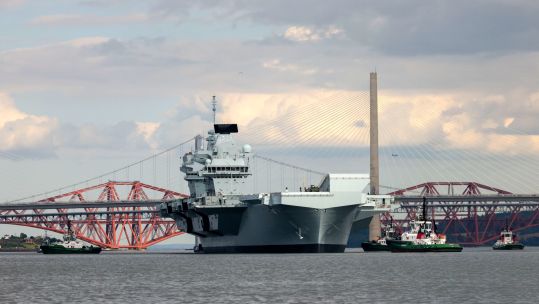 HMS Prince of Wales travelling under the Forth Bridges after nine months of repairs in Rosyth, Scotland