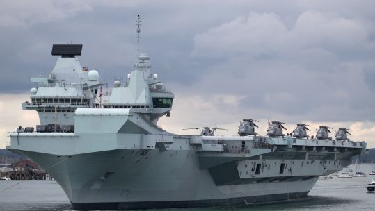 HMS Queen Elizabeth leaving Portsmouth with Merlin helicopters on deck (Picture: PA).