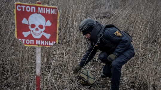 A sapper of the State Emergency Service inspects an area for mines and unexploded shells