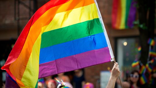 Participant with large backlit rainbow flag in the annual Gay Pride Parade as it passes through Greenwich Village