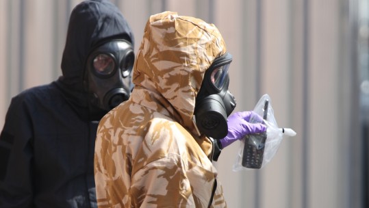 Investigators in chemical suits remove an item as they work behind screens erected in Rollestone Street, Salisbury, Wiltshire.jpg	