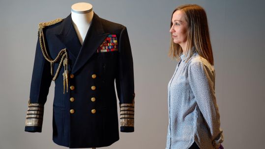 Kate Braun, curator at the National Museum of the Royal Navy, looks a naval uniform which once belonged to the Duke of Edinburgh as it goes on display
