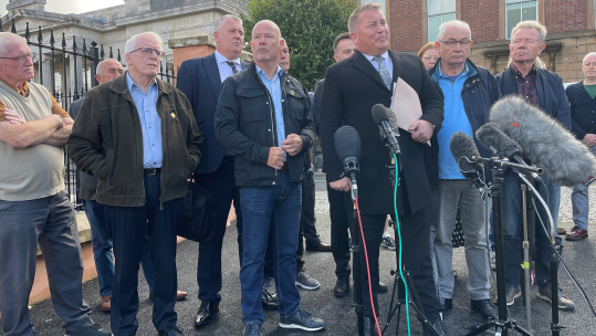 Lawyer Ciaran Shiels with the families of Bloody Sunday victims outside the the magistrates' court in Londonderry 25/08/23 CREDIT Jonathan McCambridge PA Wire