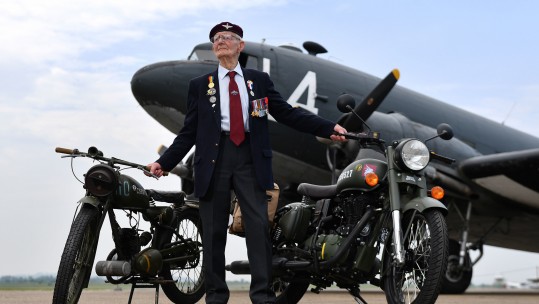 Fred Glover, 92, who served in the parachute regiment during World War II, stands on the airstrip at Imperial War Museum Duxford with a limited edition Royal Enfield 'Classic 500cc Pegasus' motorbike PA IMAGE