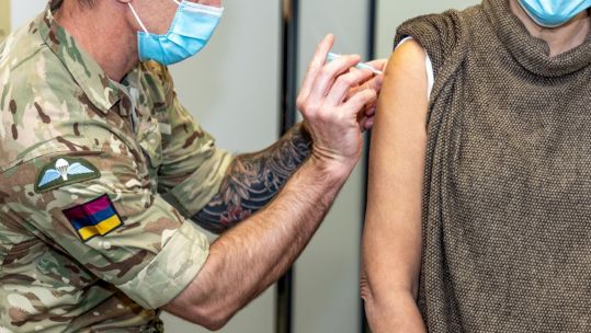 Member of the British Armed Forces administering a COVID-19 vaccination