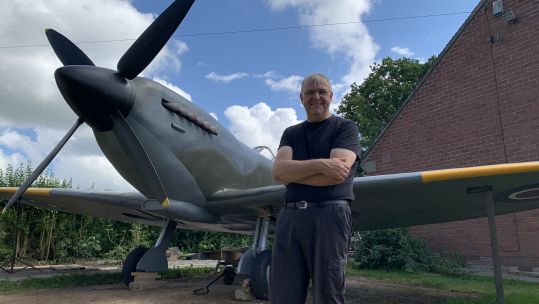 Military historian David Price next to fullscale replica model Spitfire in his garden