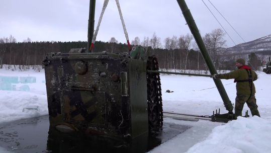Military personnel recovering an APC from under a frozen lake in Norway