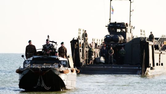  Military piper Major Trevor Macey-Lillie comes into shore on a DUKW amphibious vehicle ahead of playing a dawn lament on Gold Beach in Arromanches in Normandy, France 060624 CREDIT PA