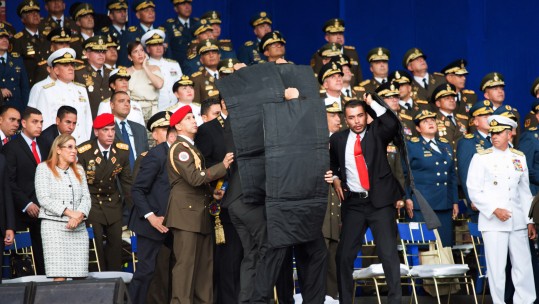 Security members protect Venezuelan President Nicolas Maduro after his speech was interrupted in Caracas, Venezuela